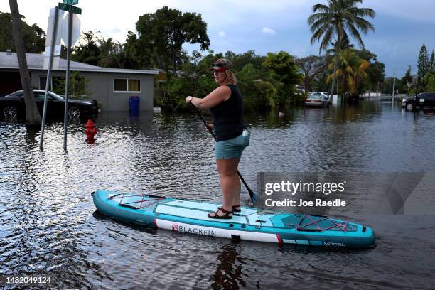 Lindsey Elf uses a paddle board to ride through a flooded street on April 13, 2023 in Fort Lauderdale, Florida. Nearly 26 inches of rain fell on Fort...