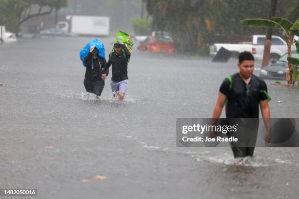 Denis Mendez, Isain Lopez, and Santiago Rojas walk through a flooded street on April 13, 2023 in Fort Lauderdale, Florida. Nearly 26 inches of rain...