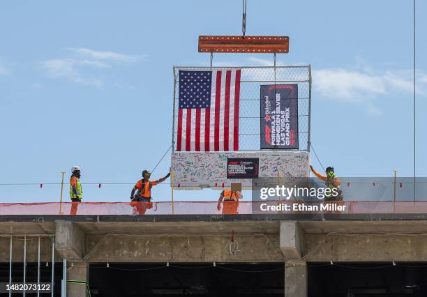 Construction workers place a track safety barrier signed by executives on top of the Las Vegas Grand Prix paddock building during a topping out event...