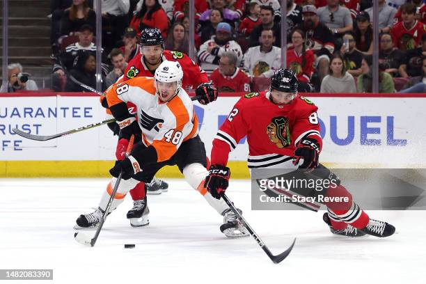Morgan Frost of the Philadelphia Flyers works for a loose puck against Caleb Jones of the Chicago Blackhawks during the first period at United Center...