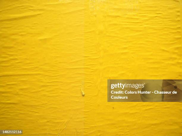 crumpled yellow paper stuck on a wall in paris, france - stickers stock-fotos und bilder