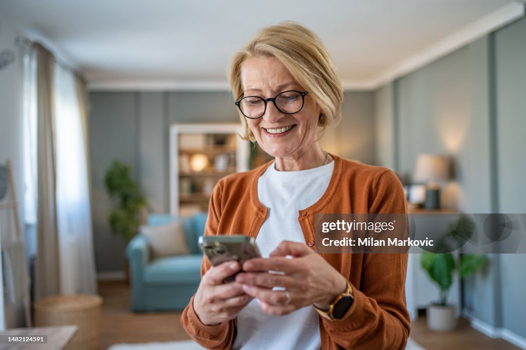 Mature woman using smart phone at home