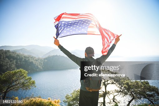 man with american flag on the background of the sea and mountains