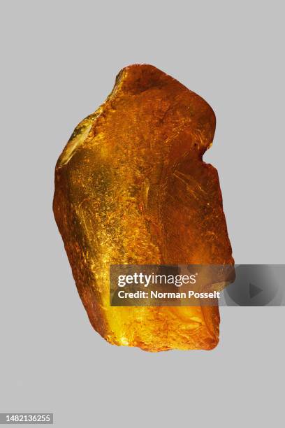 close up golden baltic amber stone on gray background - bernstein stock-fotos und bilder