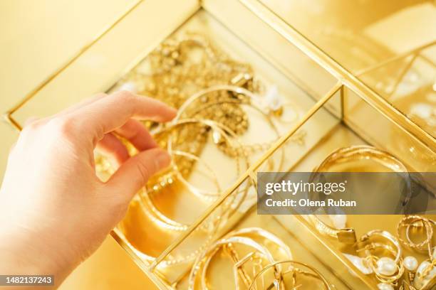 woman choosing from various gold and pearl jewelry. - bijou fotografías e imágenes de stock