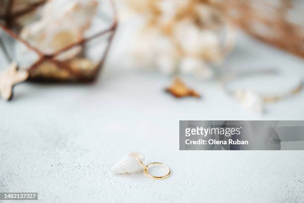 golden ring with a sea shell near blurred objects. - bijoux or stock-fotos und bilder