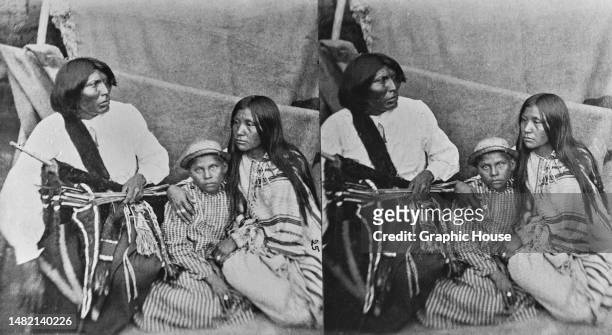 Stereoscopic image showing Comanche war chief Black Horse, with his wife, and daughter Akhah, during their confinement at Fort Marion Prison in St...