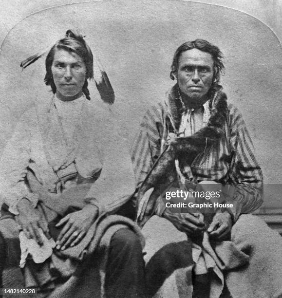 Santee men in traditional dress, one with feathers in his hair, in a studio portrait, Dakota Territory, circa 1885. The image is one half of a...