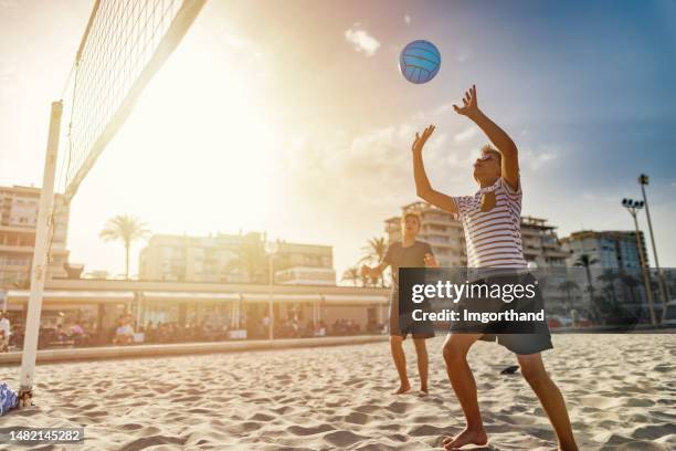 teenage kids playing volleyball on beach in city of alicante - beach volleyball stock pictures, royalty-free photos & images