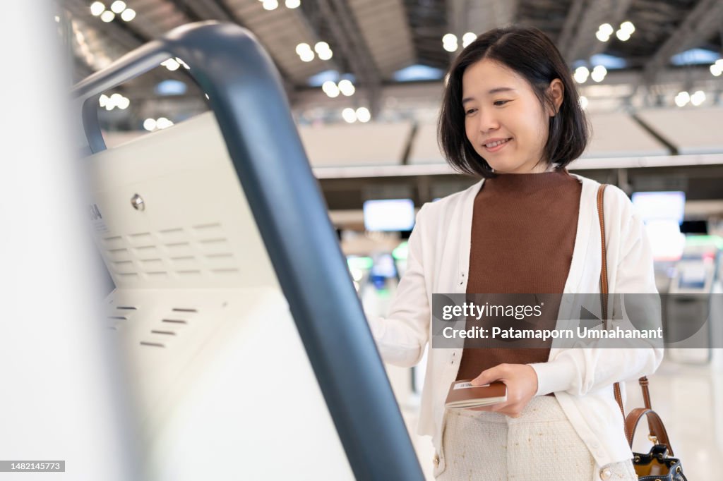 Technology facilitates fast and still has high security. Asia travel woman use kiosk automatic check in machine to check in online and get boarding pass. Scanning passport to record the passenger information in the system.