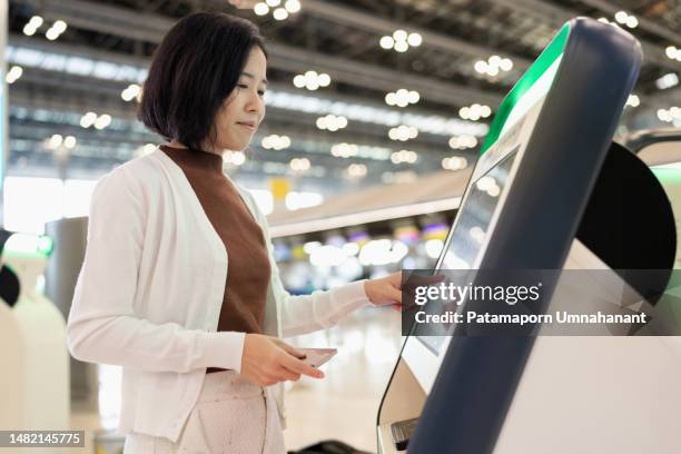 information security can use technology to control and store systematically. asia travel woman check in at automatic check in kiosk. touching screen and choose flight detail and insert passport to record data in system to create boarding pass. - booth stock pictures, royalty-free photos & images