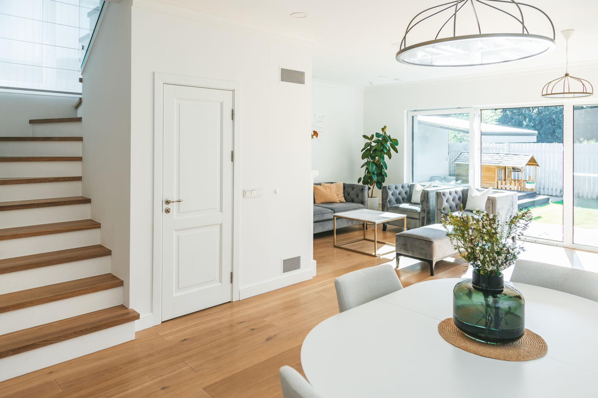 White living room with a big window and a dining room together in one space White living room with a big window and a dining room together in one space