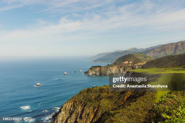 view of scenic rocky coastline during sunny day in big sur, california - monterey schiereiland stockfoto's en -beelden