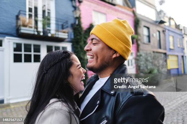 a cheerful young couple hugging in the street - freeing stock pictures, royalty-free photos & images