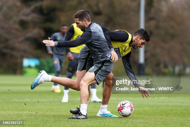 Raul Jimenez is challenged by Joao Moutinho of Wolverhampton Wanderers during a Wolverhampton Wanderers Training Session at The Sir Jack Hayward...