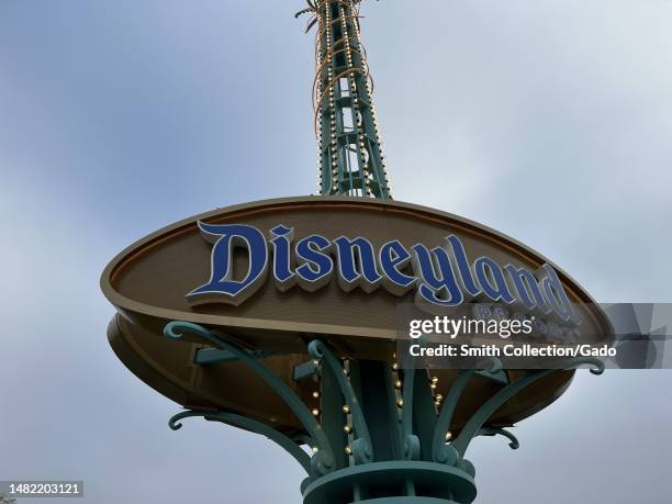 Disneyland entrance sign under a cloudy sky with metal poles and electronic signage, Anaheim, California, April 9, 2023.
