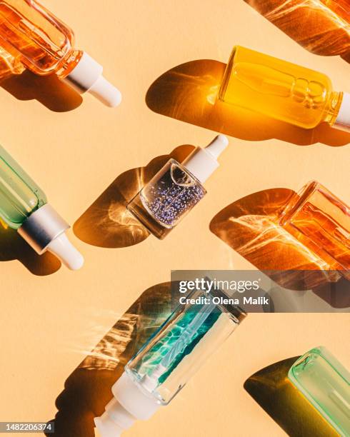assorted glass bottles with cosmetic liquids, serum or gel. vibrant trendy background of  cosmetic products, flat lay style - facial cleanser stockfoto's en -beelden