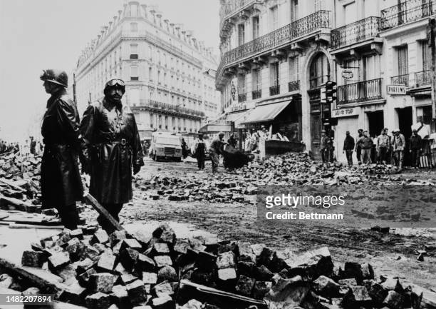 Armed gendarmes stand guard as workers remove piles of stone blocks used to build barricades during last night's protest in the Latin Quarter of...
