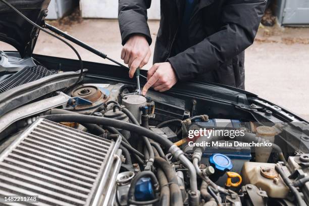 man fixing his car engine under the open hood - car mechanic stock pictures, royalty-free photos & images