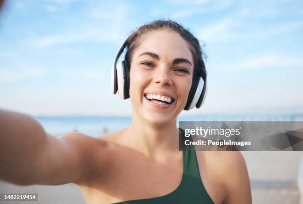 Selfie, fitness and woman headphones for outdoor training, running or exercise on video call for influencer update. Music, portrait and profile picture of sports person at beach workout or cardio