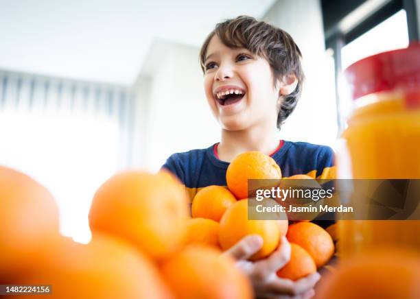 boy laughing and making orange juice - orangensaft stock-fotos und bilder