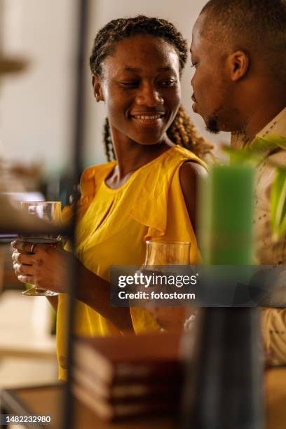 romantic couple enjoying red wine, looking and smiling at each other during a date night at home - young couple date night wine stock pictures, royalty-free photos & images