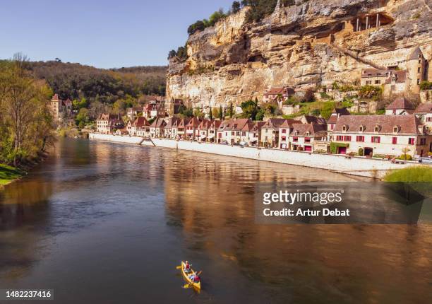 aerial view of a couple kayaking with the town of la roque gageac in the dordogne river during vacations in the south of france. - dordogne river stock pictures, royalty-free photos & images