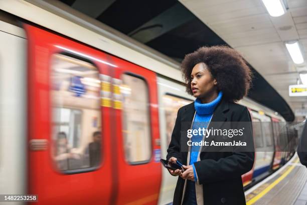 une femme noire adulte utilise le métro de londres pour rentrer chez elle après une longue journée de travail - london tube photos et images de collection