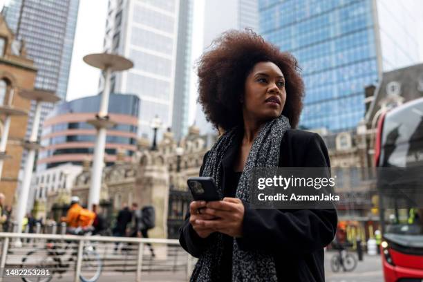 a confused adult black female checking directions on her phone while exploring london - looking around stock pictures, royalty-free photos & images