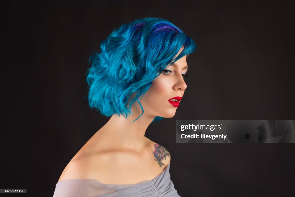 Girl with blue dyed hair in studio on black background