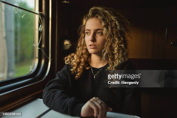 blonde curly woman traveling by train. spring journey - tåginteriör bildbanksfoton och bilder