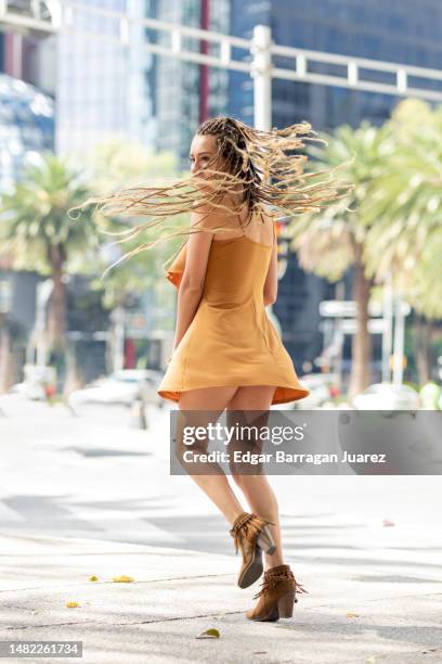 young woman in a dress standing twirling and tossing her long braided hair, on a street in mexico city - アクション映画 ストックフォトと画像