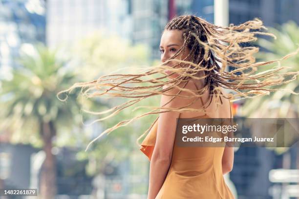 young woman with long braided hair smiling as she twirls and flies her hair - アクション映画 ストックフォトと画像