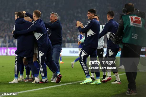 Marius Bulter of Schalke celebrates scoring his teams fourth goal of the game with teammates on the bench and Schalke Head Coach / Manager, Thomas...