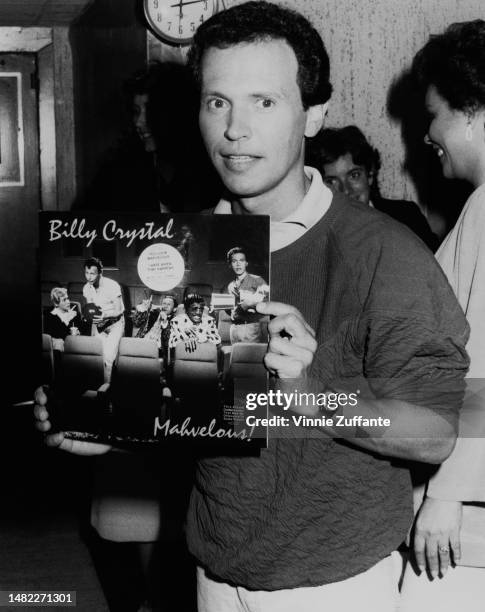 Billy Crystal poses with a copy of his first comedy/music album titled "Mahvelous", United States, circa 1980s.