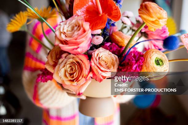 multicolored flowers arranged in a vase being held by a woman. - bunch fotografías e imágenes de stock