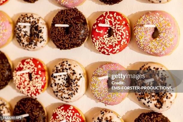 close-up of variety donuts hanging up on a board at a party - carbohidrato fotografías e imágenes de stock