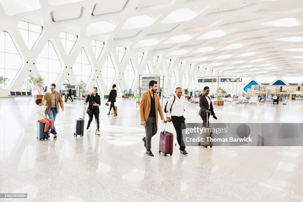 Wide shot of disabled traveler walking through airport with friend