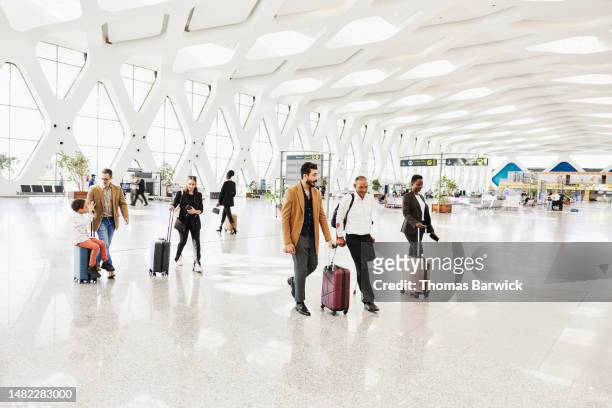 wide shot of disabled traveler walking through airport with friend - morocco interior ストックフォトと画像