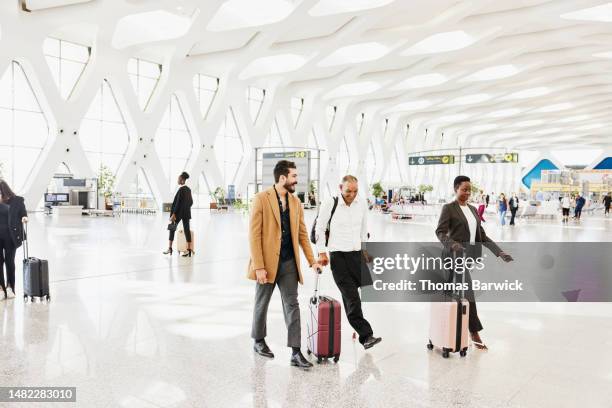 wide shot of disabled traveler walking through airport with friend - business class stock pictures, royalty-free photos & images