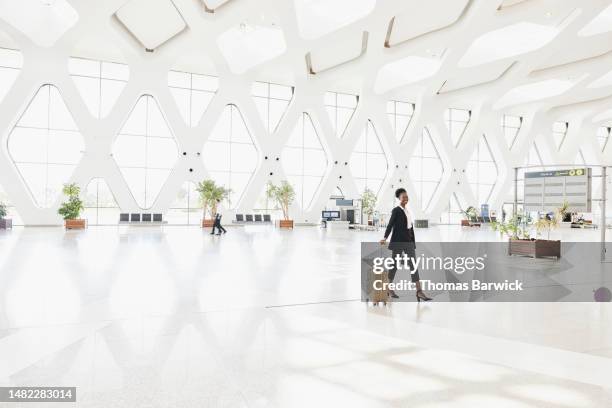 extreme wide shot of smiling businesswoman walking through airport - morocco interior ストックフォトと画像