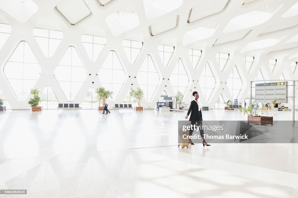 Extreme wide shot of smiling businesswoman walking through airport