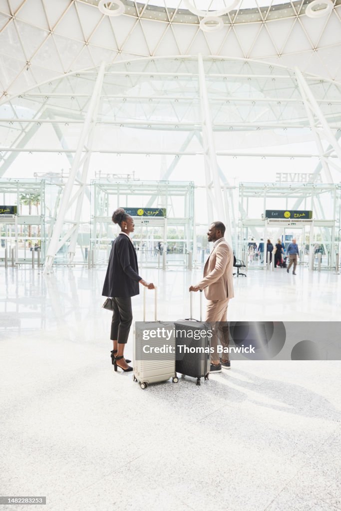 Wide shot business colleagues in discussion in airport arrivals