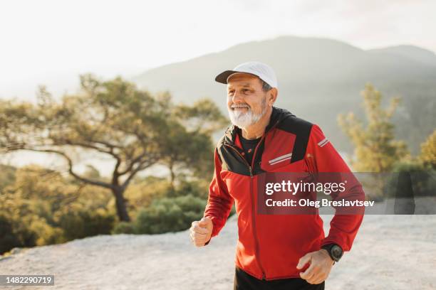 happy senior man enjoying running at sunset by the nature - red cross photos et images de collection