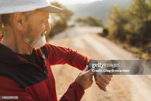 aged man satisfied with running results. checking activity data on smartwatches - smart watch stock pictures, royalty-free photos & images