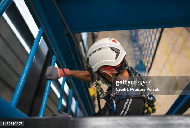 construction worker wearing safety harness and safety line working at high place - rope high rescue photos et images de collection
