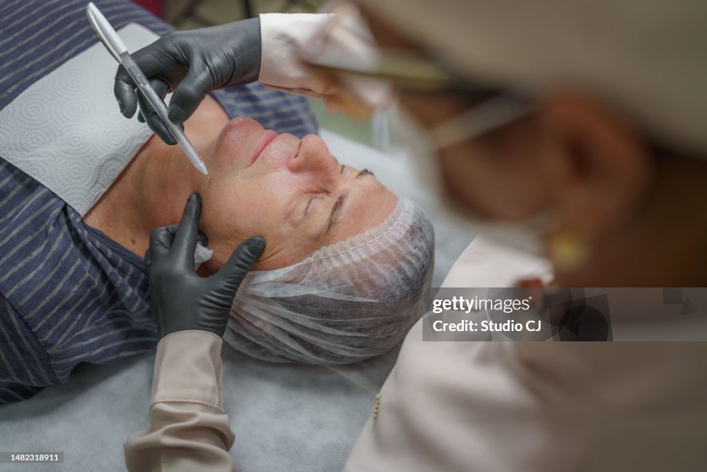 Esteticista que prepara marcas para la aplicación de relleno