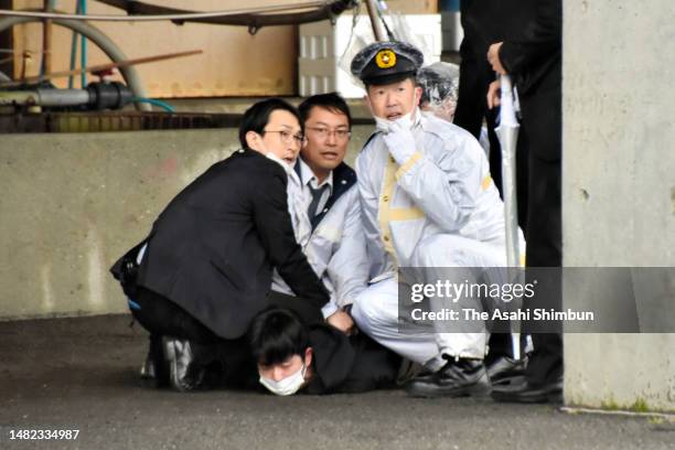 Man is seized by police officers after throwing cylinder-shaped objects prior to the election support speech by Prime Minister Fumio Kishida at...