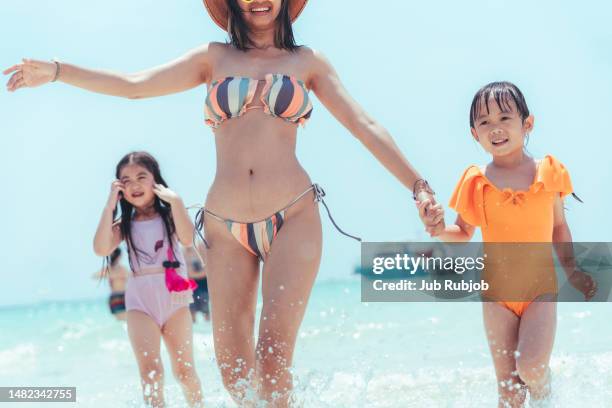 three asian sisters are running and playing on the clear water beach on an island in east asia. - mother and child in water at beach stock pictures, royalty-free photos & images