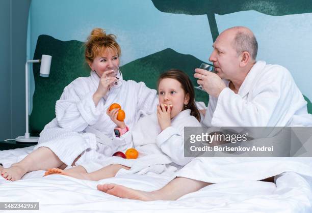the family of caucasians is resting. a 50-year-old man, a 40-year-old woman and a 7-year-old girl in white coats are relaxing, drinking wine and eating fruit. - lebanon wine stock pictures, royalty-free photos & images